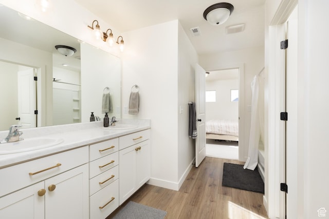 bathroom featuring wood finished floors, double vanity, a sink, and visible vents