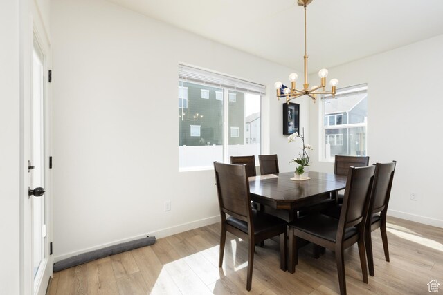dining room with a notable chandelier, light wood-type flooring, and baseboards