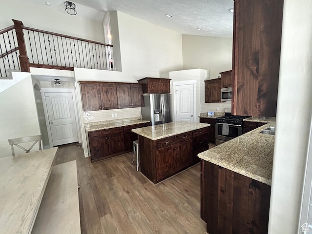 10124 S Autumn Breeze Ln W, South Jordan, UT 84009 - kitchen featuring high vaulted ceiling, dark brown cabinets, a kitchen island, appliances with stainless steel finishes, and wood finished floors