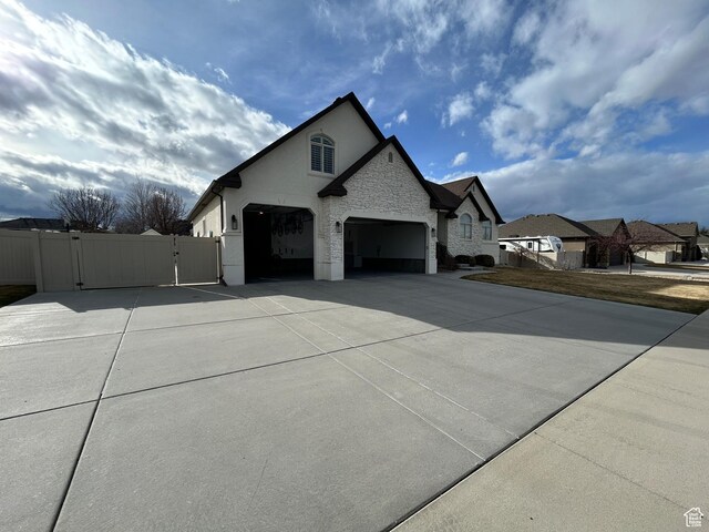 10124 S Autumn Breeze Ln W, South Jordan, UT 84009 - view of side of property with concrete driveway, stucco siding, stone siding, an attached garage, and a gate