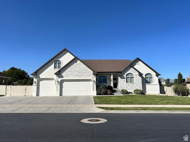 french provincial home featuring fence, a front yard, stone siding, and a gate