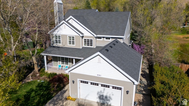 6041 S 2230 E, Holladay, UT 84121 - exterior space featuring a chimney, driveway, covered porch, an attached garage, and roof with shingles