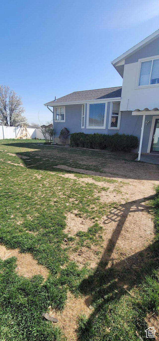 view of home's exterior featuring fence, a lawn, and stucco siding