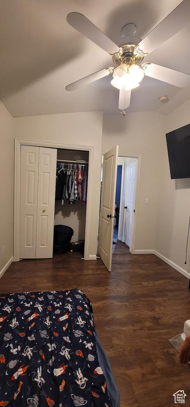 unfurnished bedroom with dark wood-type flooring, a closet, baseboards, and a ceiling fan