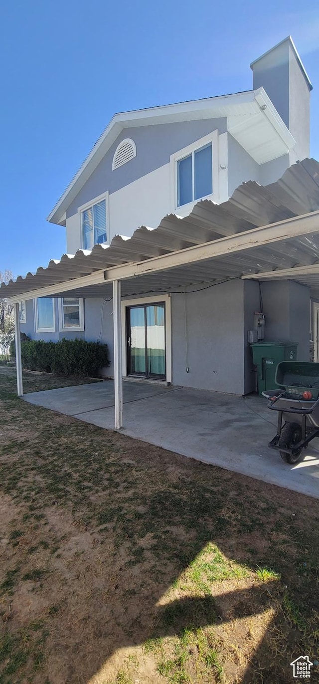 rear view of house with a patio area, a lawn, and stucco siding