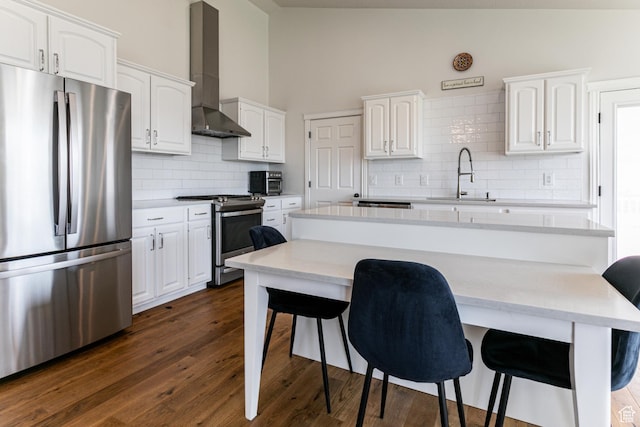 4781 W 4100 S, West Haven, UT 84401 - kitchen featuring appliances with stainless steel finishes, a sink, wall chimney exhaust hood, a breakfast bar area, and vaulted ceiling