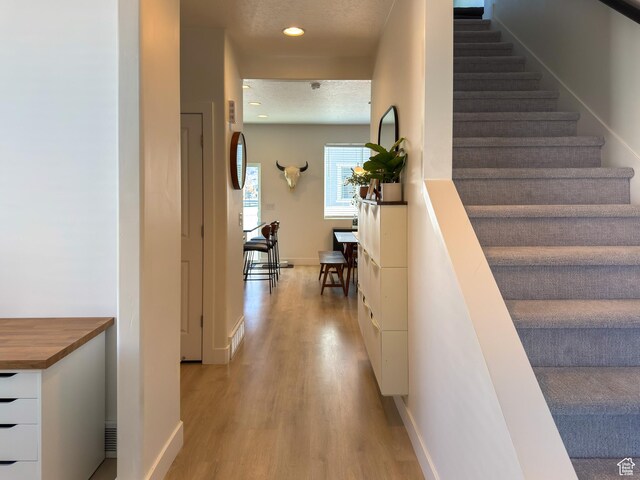 5051 W Bilston Ln S, Herriman, UT 84096 - hallway featuring baseboards, a textured ceiling, recessed lighting, light wood finished floors, and stairway