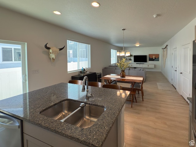 5051 W Bilston Ln S, Herriman, UT 84096 - kitchen featuring dishwasher, a sink, open floor plan, light wood-style floors, and dark stone counters