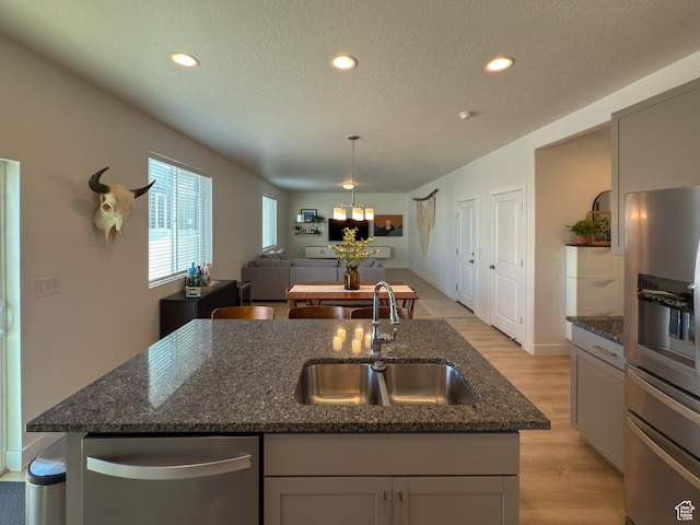 5051 W Bilston Ln S, Herriman, UT 84096 - kitchen with dark stone counters, an island with sink, light wood-type flooring, a sink, and open floor plan