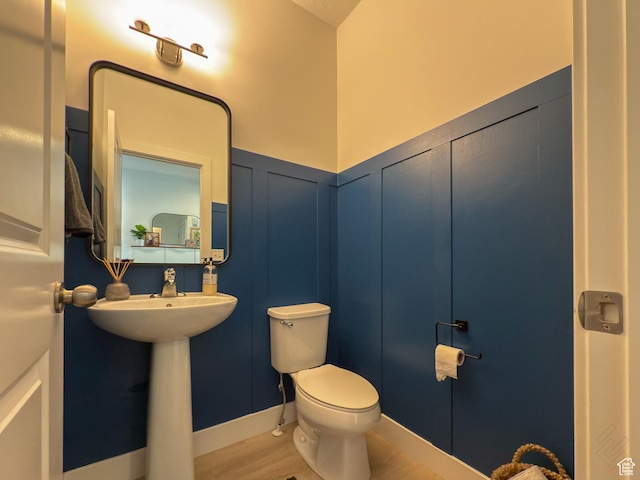 5051 W Bilston Ln S, Herriman, UT 84096 - half bathroom featuring a wainscoted wall, toilet, a decorative wall, a sink, and wood finished floors