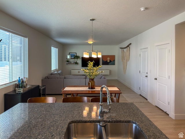 5051 W Bilston Ln S, Herriman, UT 84096 - kitchen featuring light wood-style flooring, a textured ceiling, a chandelier, dark stone countertops, and a sink