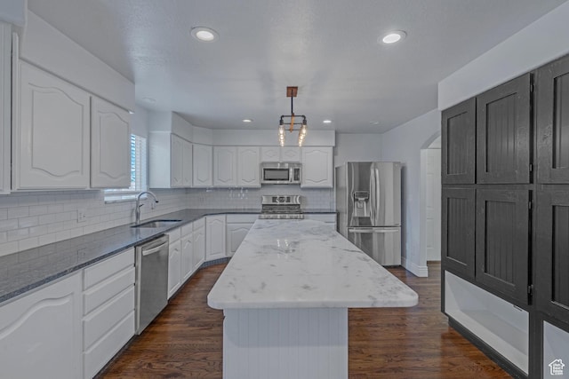 8079 S Juniper Ct, South Weber, UT 84405 - kitchen featuring appliances with stainless steel finishes, a center island, dark stone counters, dark wood finished floors, and a sink