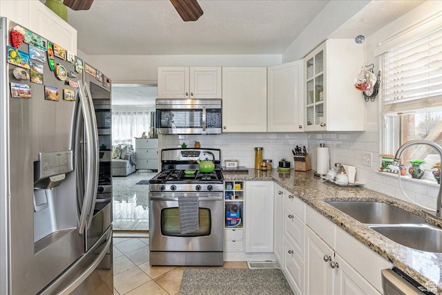 3165 S 2000 E, Millcreek, UT 84109 - kitchen with appliances with stainless steel finishes, white cabinets, a healthy amount of sunlight, decorative backsplash, and a sink