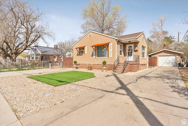 bungalow-style home featuring an outbuilding, a garage, stucco siding, and fence