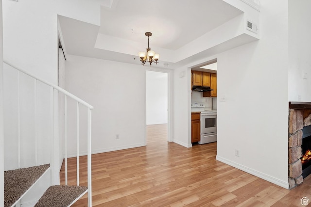 6831 N 2200 W Unit 12K, Park City, UT 84098 - unfurnished living room featuring a stone fireplace, an inviting chandelier, light wood-style flooring, visible vents, and a tray ceiling