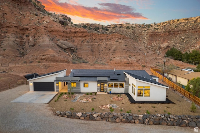 160 W Pebble, Rockville, UT 84763 - view of front of house featuring an attached garage, fence, driveway, solar panels, and stucco siding