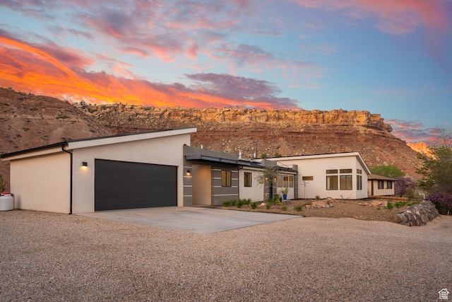 view of front of property with a mountain view, roof mounted solar panels, a garage, stucco siding, and driveway