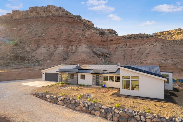 160 W Pebble, Rockville, UT 84763 - rear view of property with stucco siding, roof mounted solar panels, concrete driveway, metal roof, and a garage