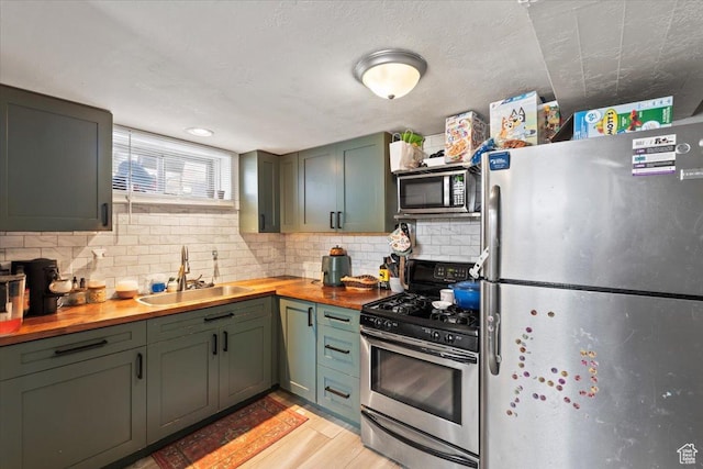 kitchen with a sink, wooden counters, green cabinets, and stainless steel appliances