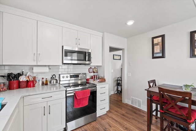 kitchen with white cabinets, visible vents, appliances with stainless steel finishes, light countertops, and decorative backsplash
