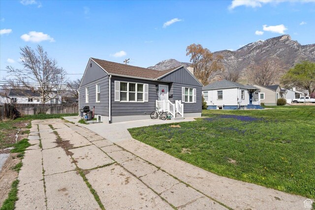 view of front of house with board and batten siding, a mountain view, fence, and a front lawn