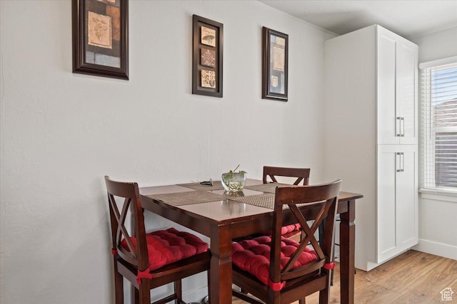 dining area featuring light wood-style flooring and baseboards