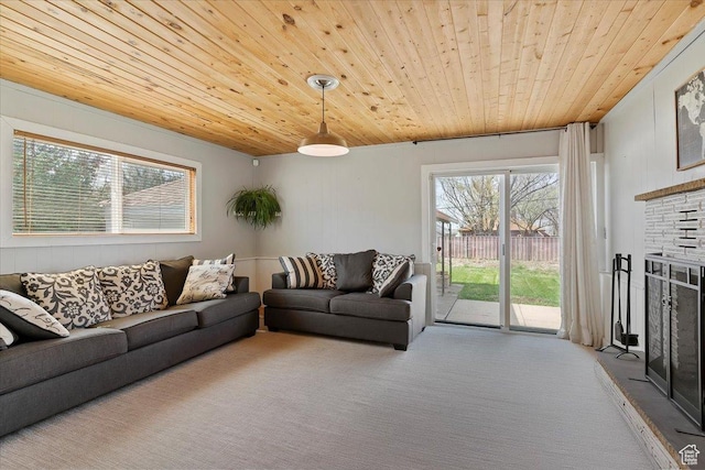 living area featuring a fireplace with raised hearth, carpet flooring, and wood ceiling