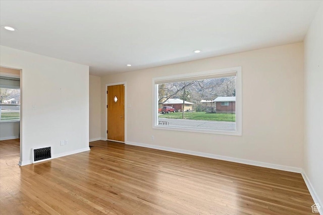 empty room with light wood finished floors, visible vents, baseboards, and a healthy amount of sunlight