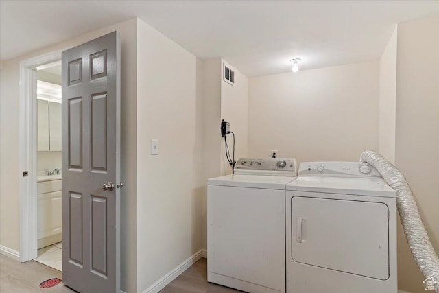 laundry area with visible vents, baseboards, a sink, laundry area, and light wood finished floors