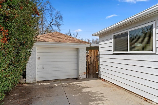 detached garage with concrete driveway and fence