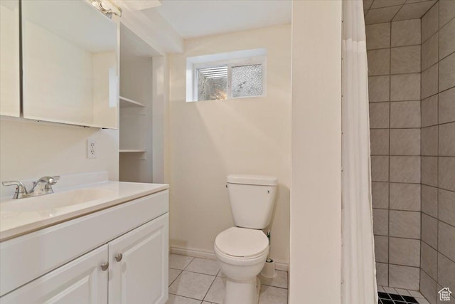 bathroom with toilet, vanity, tile patterned flooring, and a tile shower