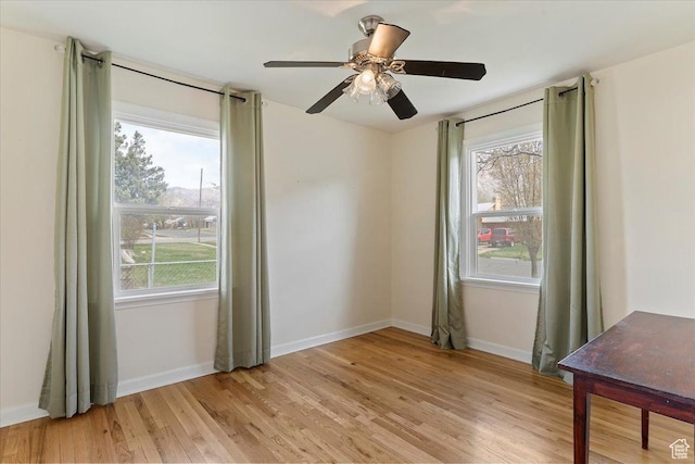 spare room with light wood-style flooring, a ceiling fan, and baseboards