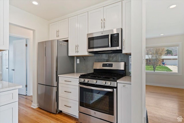 kitchen with light wood-style floors, tasteful backsplash, white cabinets, recessed lighting, and appliances with stainless steel finishes