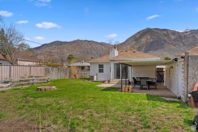 back of house featuring a chimney, a fire pit, entry steps, a fenced backyard, and a yard