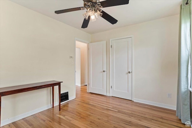spare room featuring ceiling fan, visible vents, baseboards, and light wood-style flooring