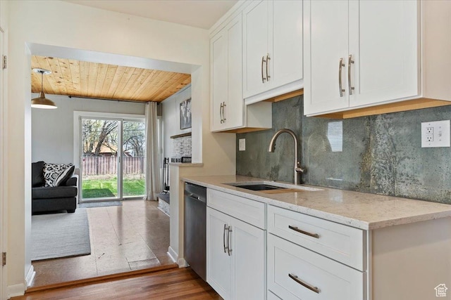 kitchen with stainless steel dishwasher, white cabinets, wood finished floors, a sink, and decorative backsplash