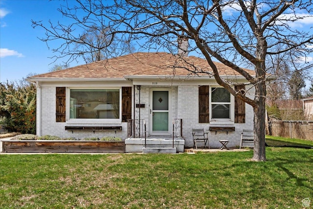 bungalow-style house with roof with shingles, a front yard, and fence