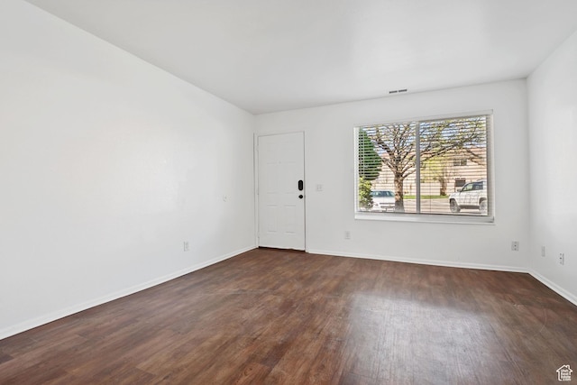 empty room with visible vents, baseboards, and dark wood-style floors