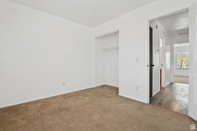unfurnished bedroom with a closet, carpet, baseboards, and attic access