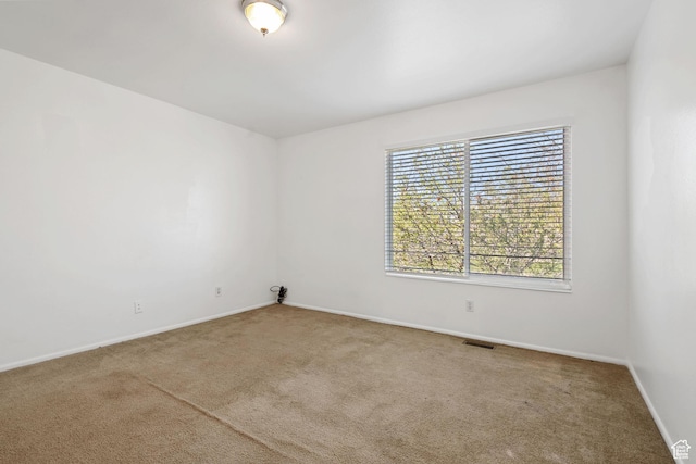 carpeted spare room with visible vents and baseboards