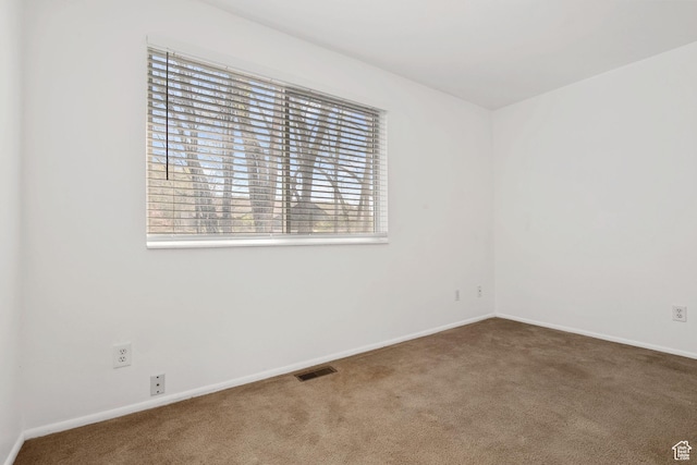 empty room featuring carpet, visible vents, and baseboards