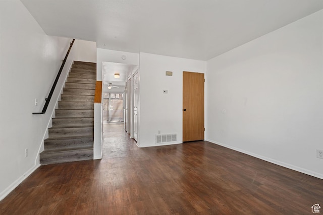 unfurnished living room with stairs, visible vents, baseboards, and wood finished floors