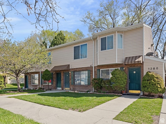 view of property featuring brick siding and a front lawn