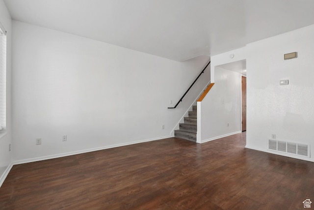 unfurnished living room with visible vents, baseboards, wood finished floors, and stairs
