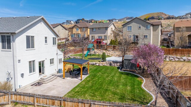 exterior space with a residential view, a mountain view, a patio area, a fenced backyard, and a playground