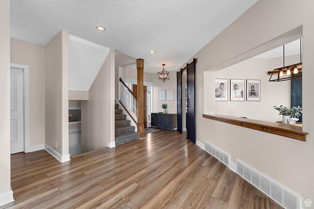 interior space featuring stairway, visible vents, an inviting chandelier, and wood finished floors