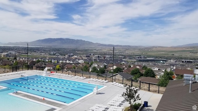 pool with a mountain view, a residential view, fence, and a patio