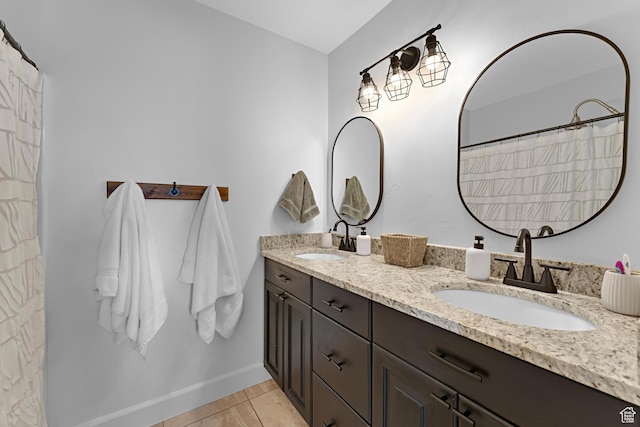 full bathroom featuring a sink, tile patterned floors, baseboards, and double vanity