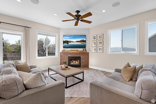 living room featuring ceiling fan, light wood finished floors, recessed lighting, and a fireplace