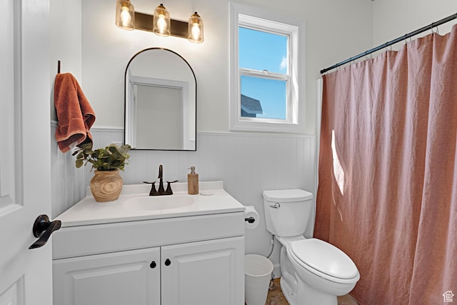 full bath with toilet, vanity, and wainscoting